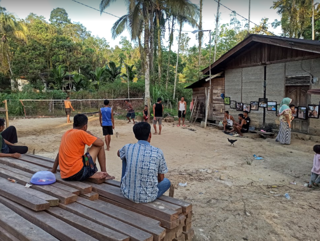 Community members gathering and playing badminton in Lubuk Bigau Village