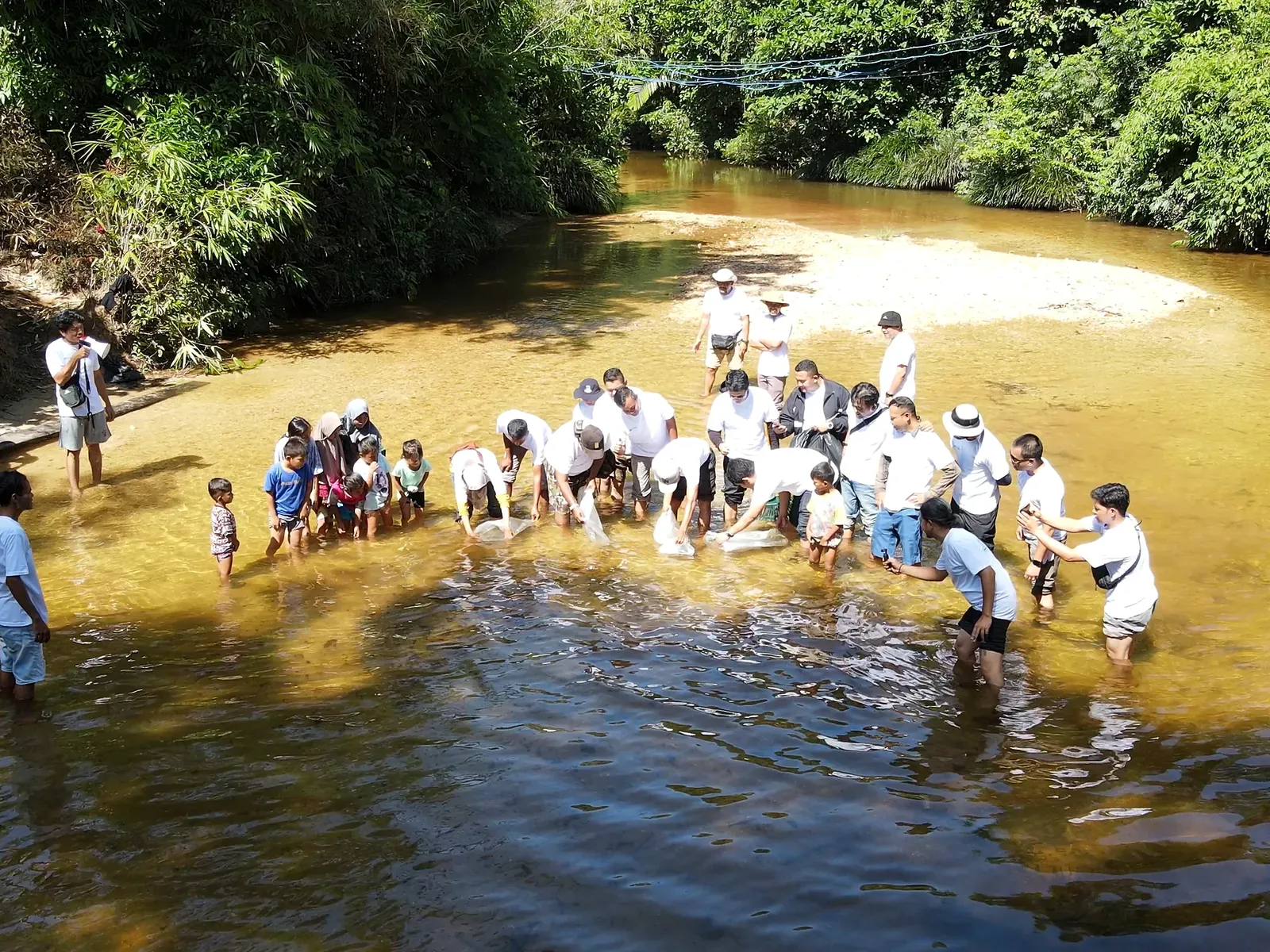 A group of community members standing together in a shallow forest river during a conservation activity.