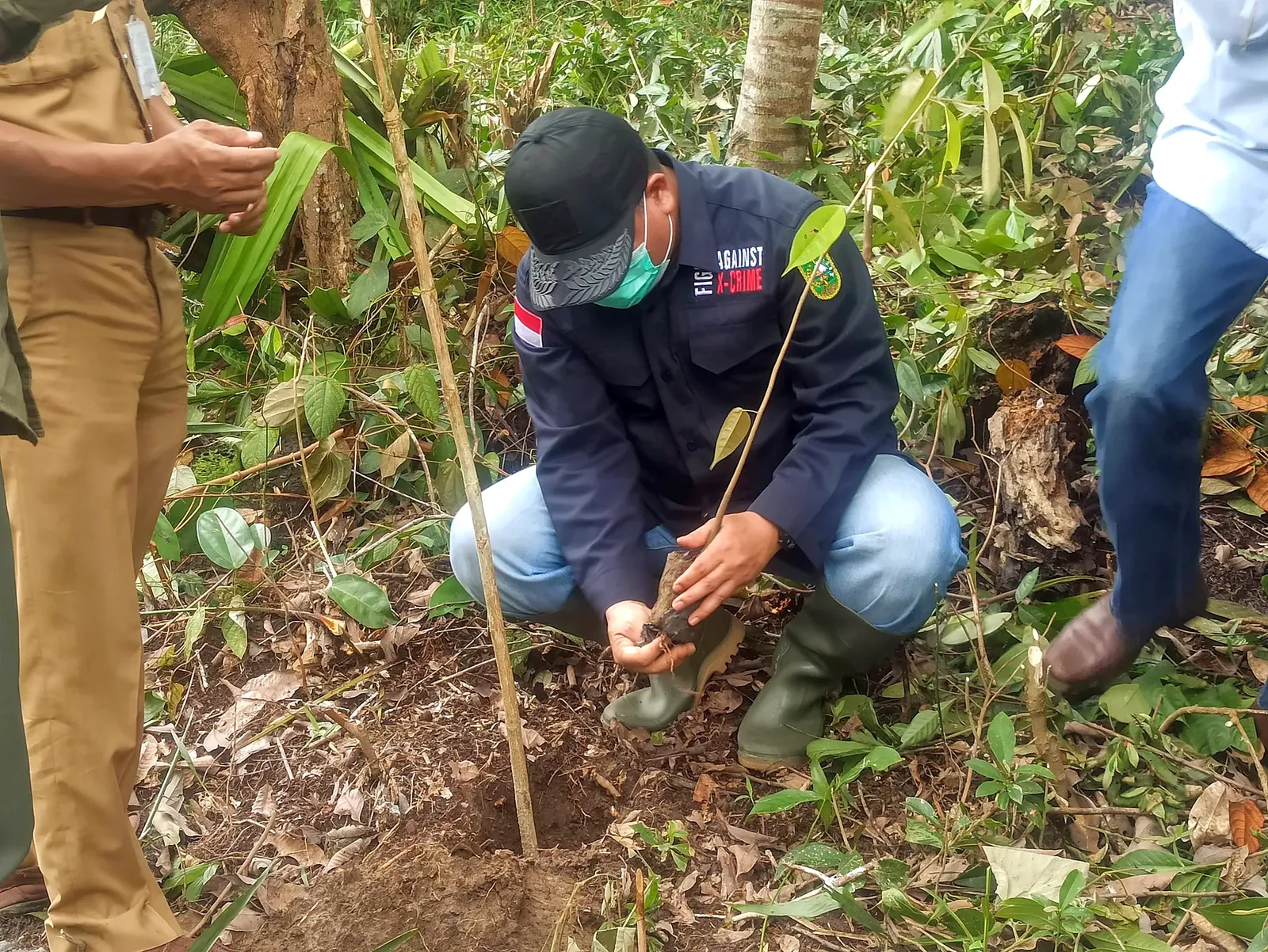 Community members planting a young tree in a forest restoration area.