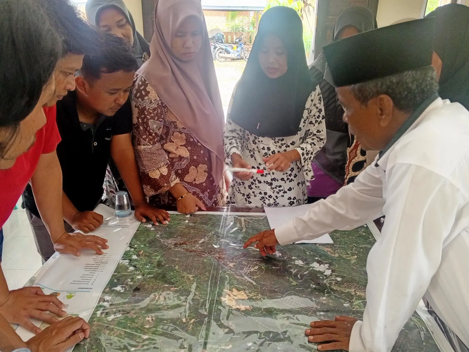 Community representatives discussing a large land-use map during participatory planning.