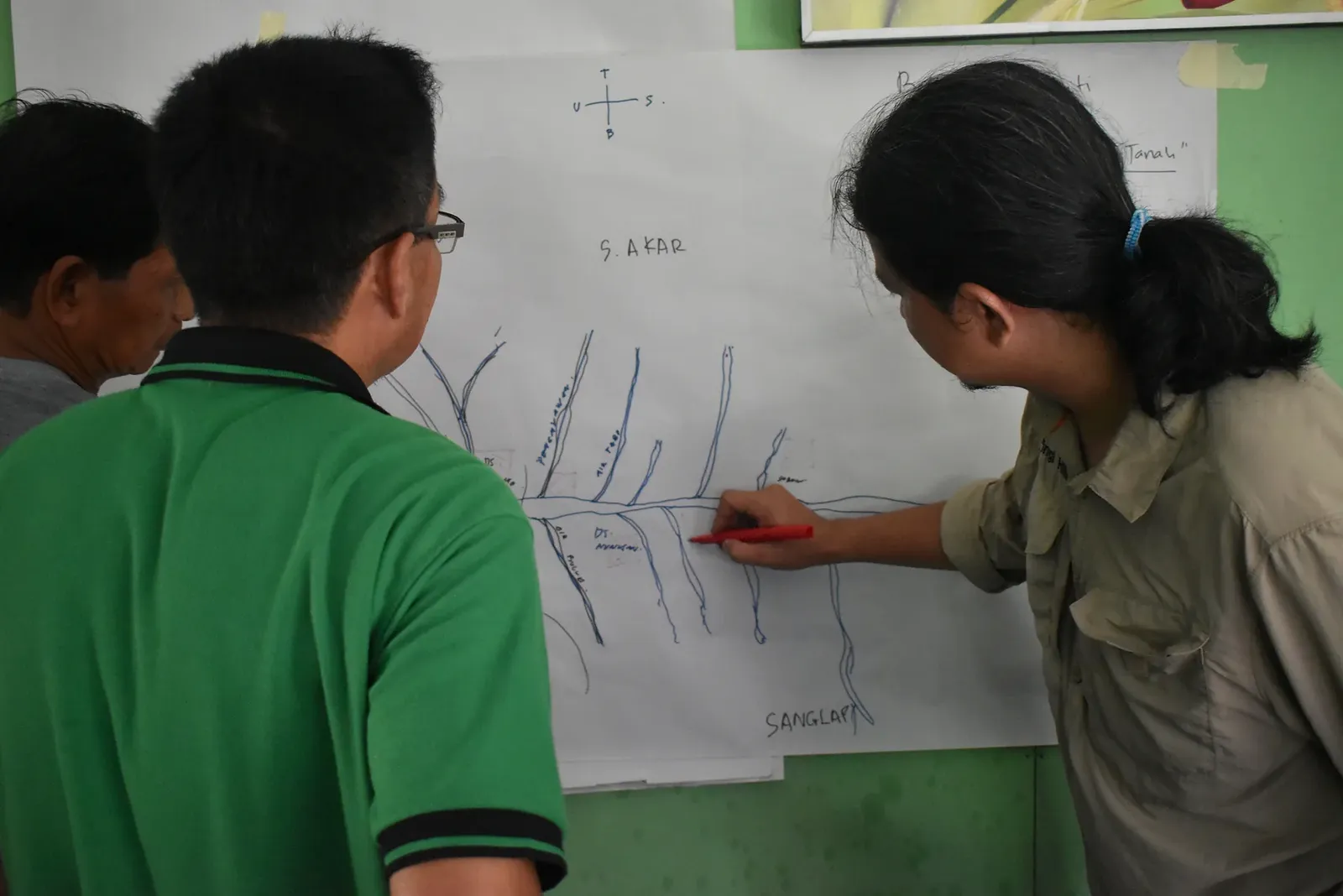 Community participants drawing and discussing a diagram during a participatory research activity.