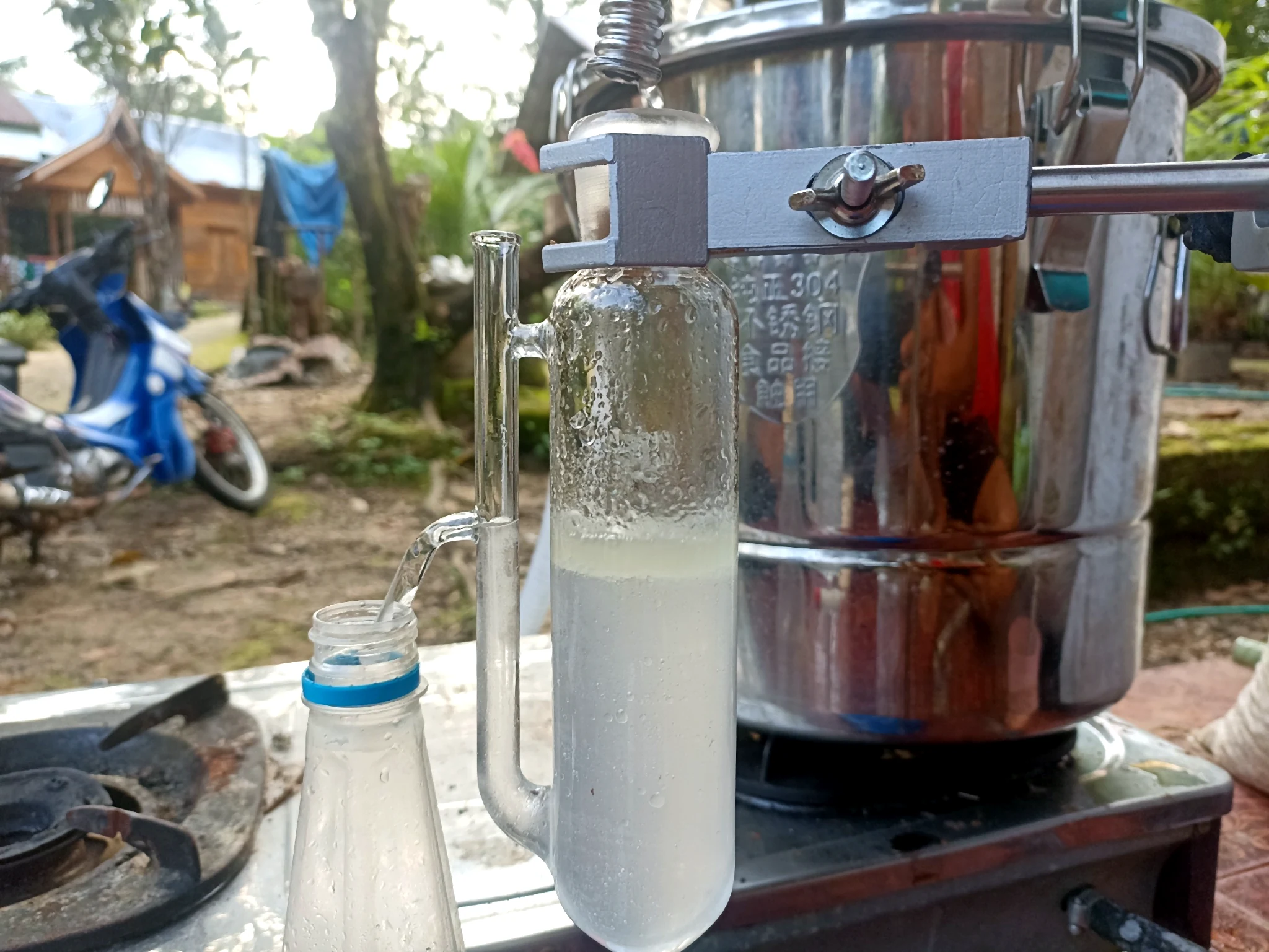 Tabung kaca berembun dan botol penampung berada di depan perangkat penyulingan logam.