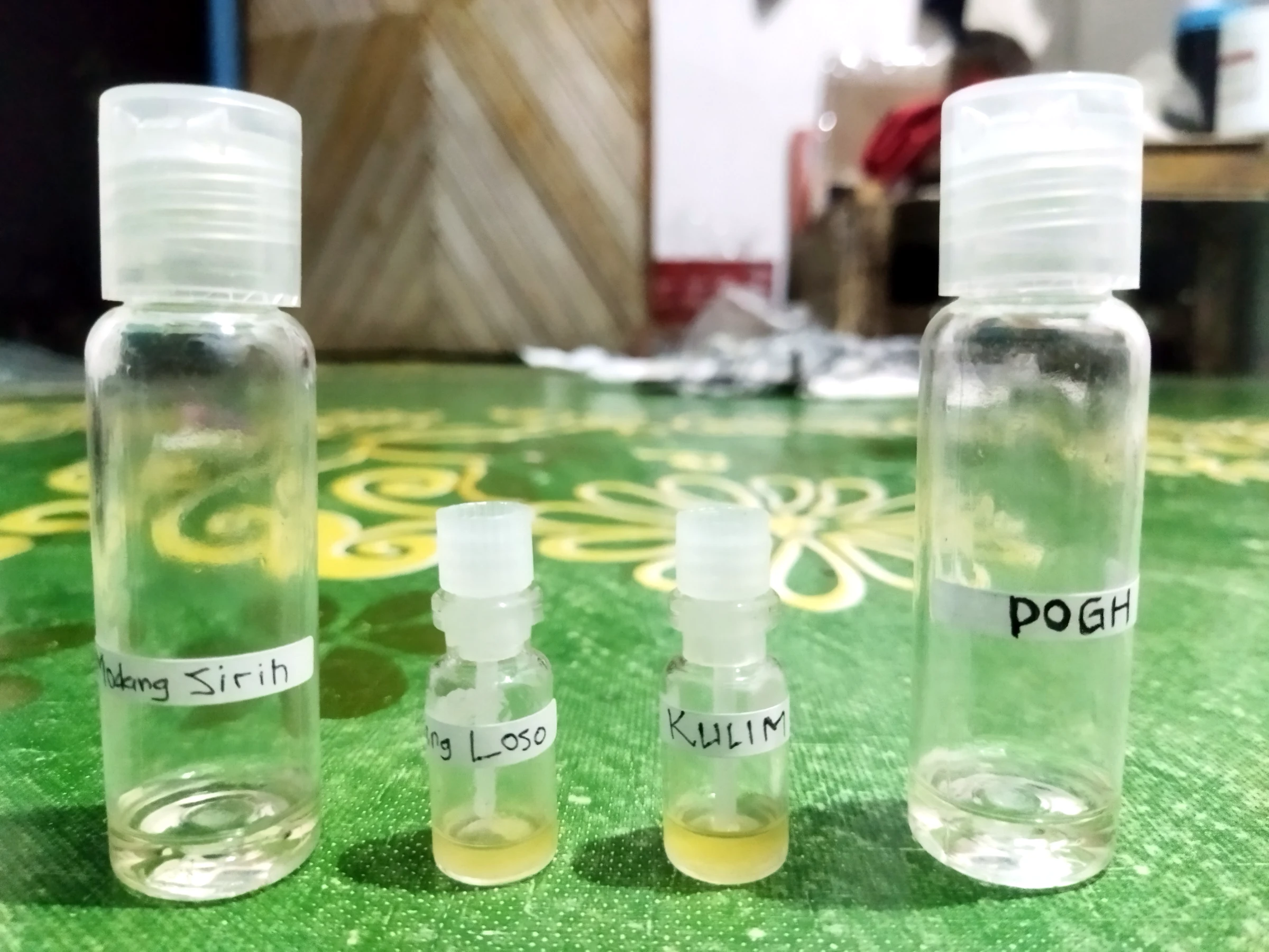 Four labelled sample bottles containing clear and pale-yellow liquid from distillation tests.