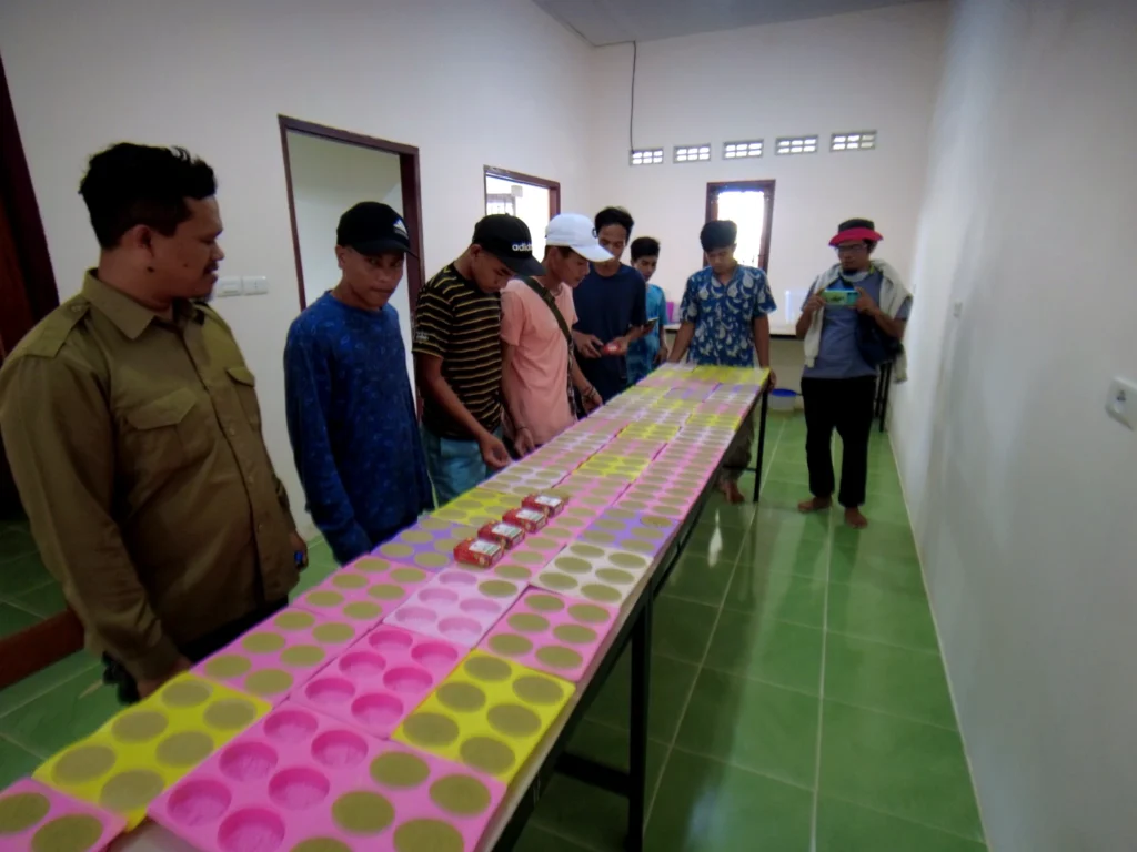 A group of people standing around a long table displaying soap products during a study visit.